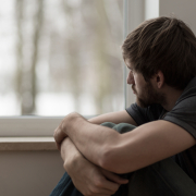 does trauma cause bipolar disorder Young man staring out the window thinking does trauma cause bipolar disorder.