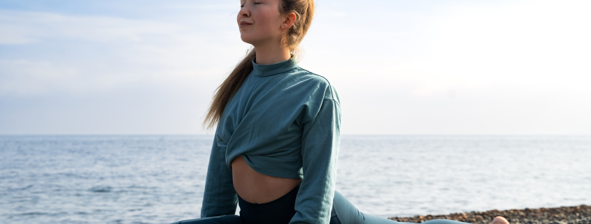 Woman practicing yoga by the sea after asking how long does it take to release trauma from hips.